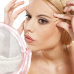 worried young woman checking her wrinkles around her eyes