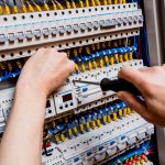 The man is repairing the switchboard voltage with automatic switches.
