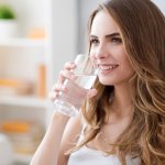 Positive woman drinking water