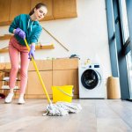 low angle view of young woman cleaning home with mop