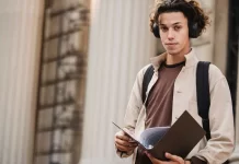 Jak wybrać odpowiednią specjalizację w trakcie studiów Student z teczką i słuchawkami przed budynkiem uniwersytetu.