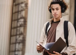 Jak wybrać odpowiednią specjalizację w trakcie studiów Student z teczką i słuchawkami przed budynkiem uniwersytetu.